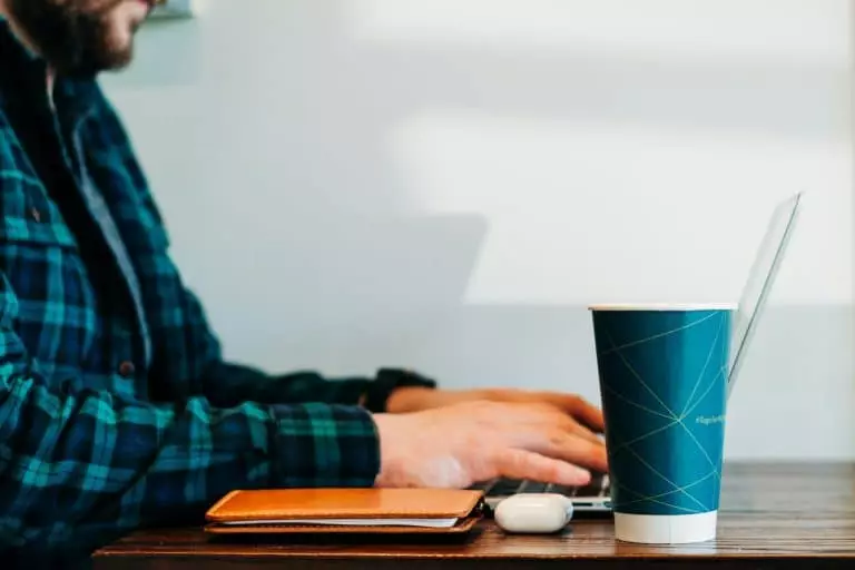 Travailleurs temporaires : un atout pour la flexibilité des entreprises man wearing blue and green plaid collared button-up long-sleeved shirt sitting while using laptop computer