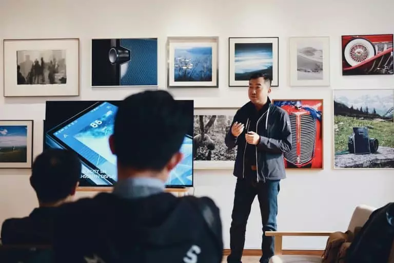 Les secrets des conférenciers révélés : comment ils boostent la motivation au travail sans effort Man Beside Flat Screen Television With Photos Background