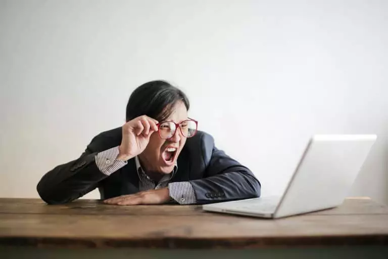 Votre employeur refuse le pont du 15 août : découvrez vos droits et les actions à entreprendre Modern Asian man in jacket and glasses looking at laptop and screaming with mouth wide opened on white background