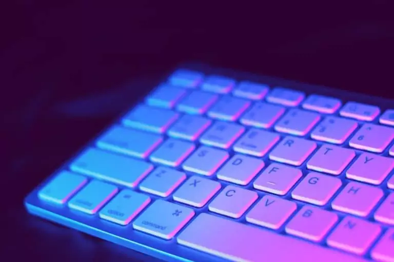 Ce bug surprenant de Booking.com : quand une simple faute de frappe menace vos vacances Close-up of a modern keyboard illuminated with vibrant purple and blue neon lighting.