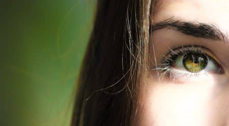 A detailed close-up of a woman's eye with green iris, capturing beauty detail.