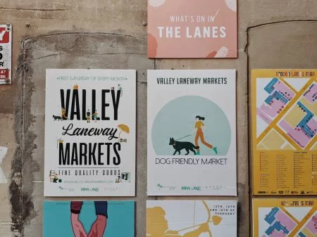 Comment les startups utilisent le marketing imprimé pour se démarquer dans des marchés saturés par le digital Promotional posters for Valley Laneway Markets in Brisbane showcasing event details and vibrant illustrations.