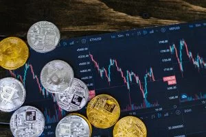 Tirer profit des périodes creuses et des revenus en berne Close-up of gold and silver cryptocurrency coins on a digital trading chart.
