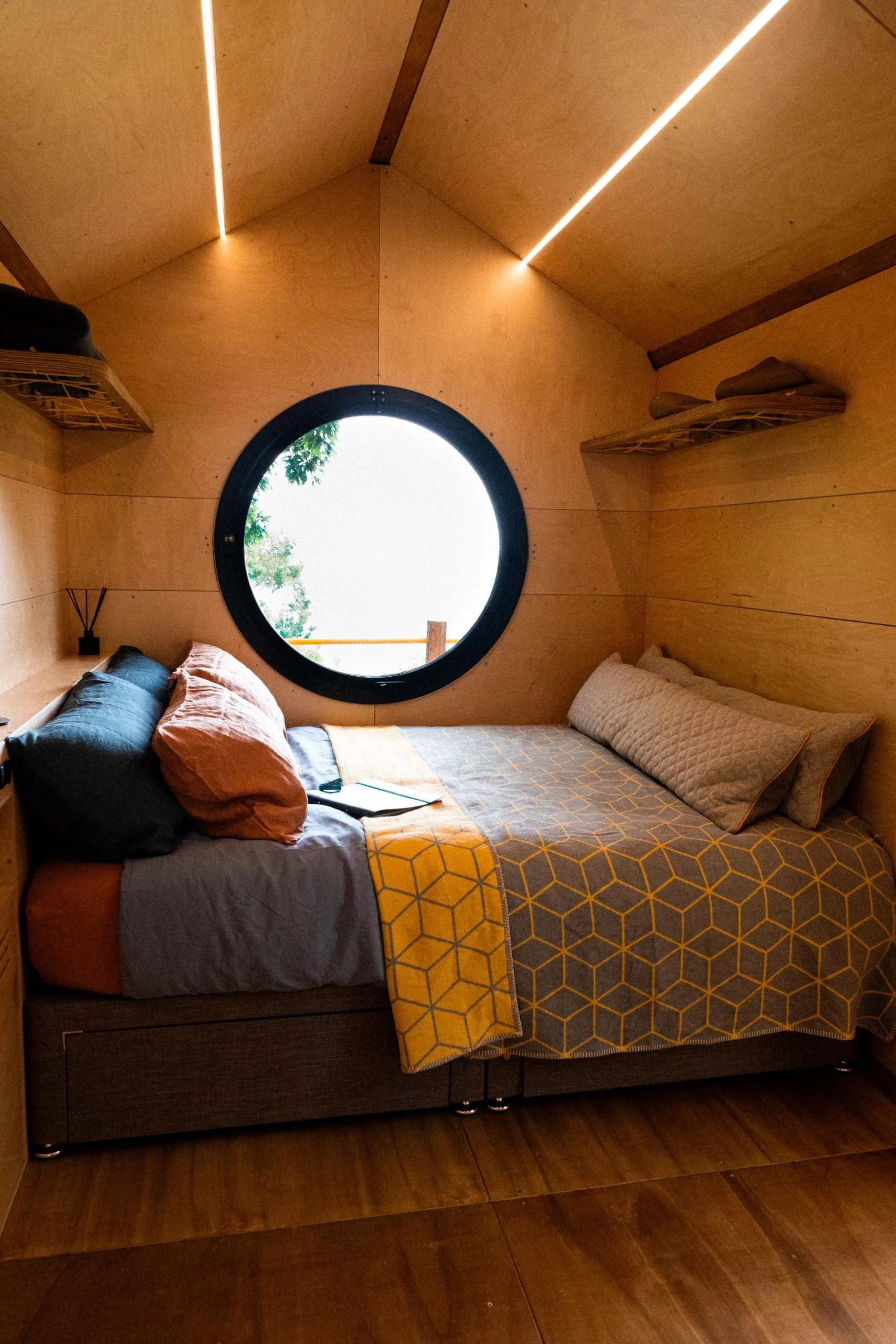 Le modèle Birdhouse Modular présenté comprend une chambre avec une fenêtre ronde façon hublot et un lit double king size