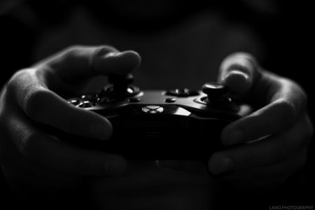 Comment l’industrie du jeu illustre le tempo de l’évolution technologique Close-up of hands holding a game controller in a monochrome setting, capturing the essence of gaming.