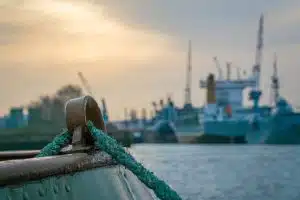 CMA CGM : Rodolphe Saadé confie à l’Inde la construction de ses navires GNL Close-up of dock with ships in industrial harbor at sunset, highlighting maritime industry.