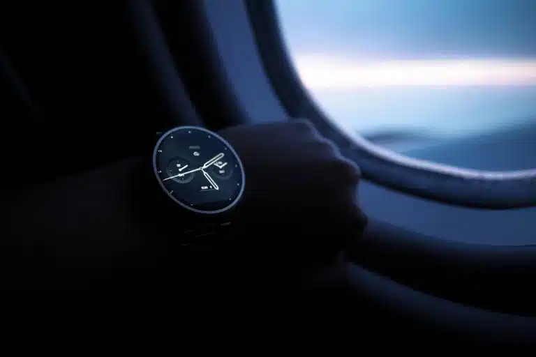 Montres automatiques, comment reconnaître un modèle fiable et performant A smartwatch on a wrist shown against an airplane window view during flight.