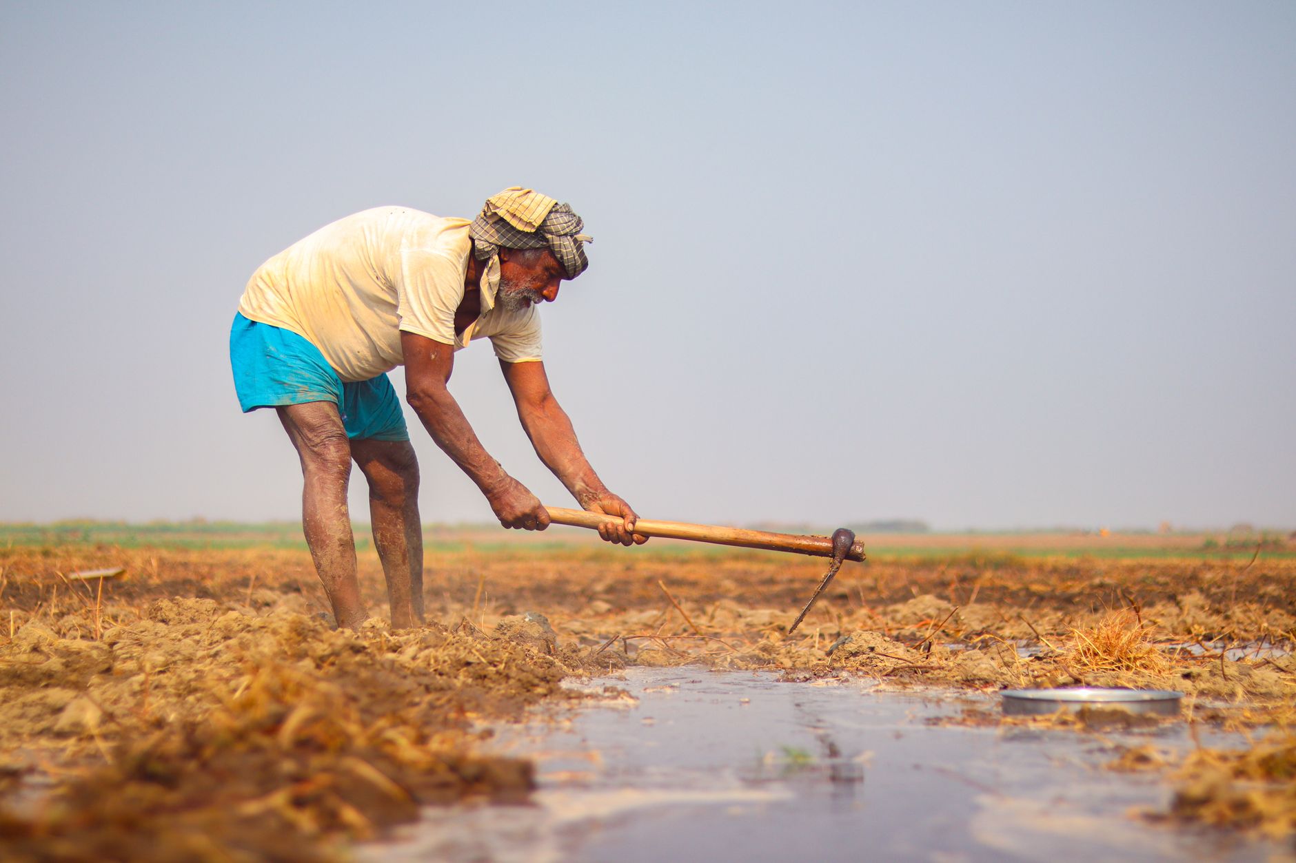 Un agriculteur maniant un outil à main pour creuser la terre dans un champ agricole.